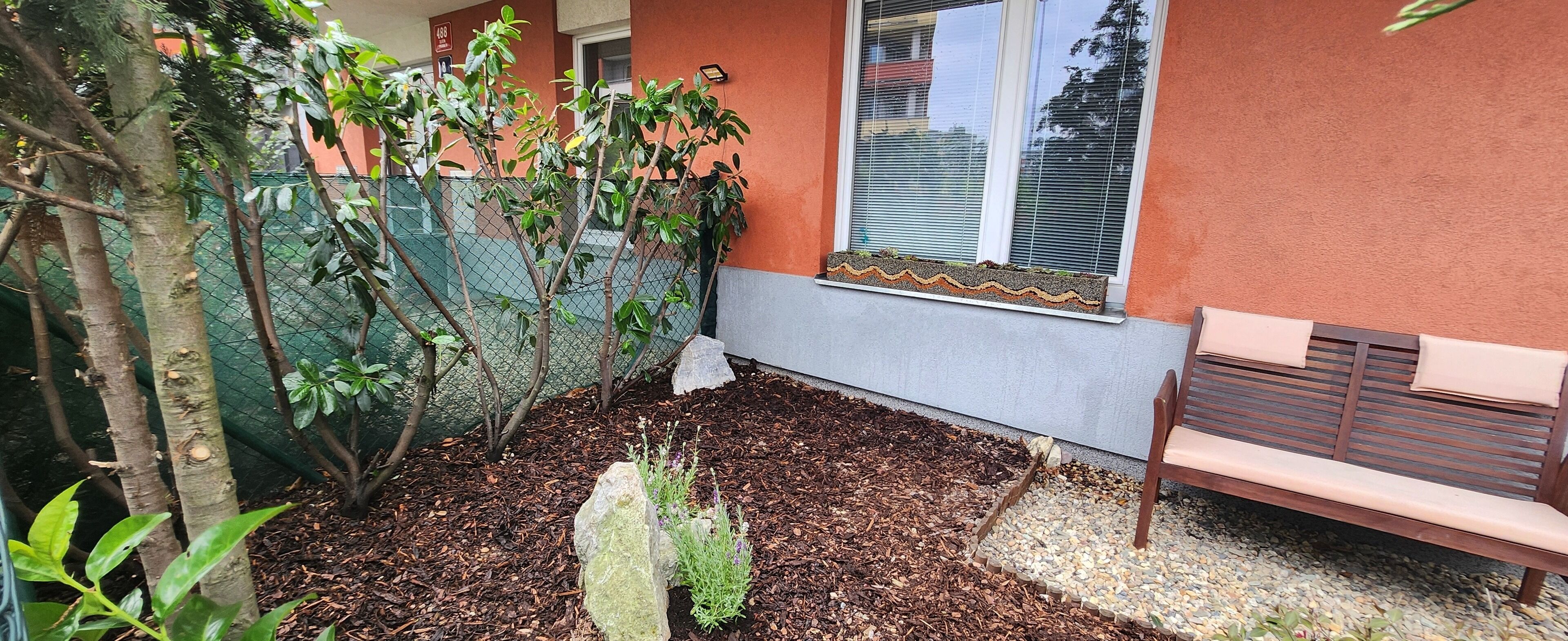 Un pequeño espacio al aire libre con un banco, una jardinera de piedra y una cerca.