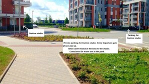 A modern apartment building with a paved walkway leading to a parking area.