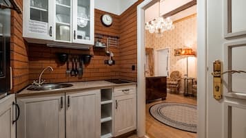 A kitchen with a brick wall, white cabinets, and a clock.