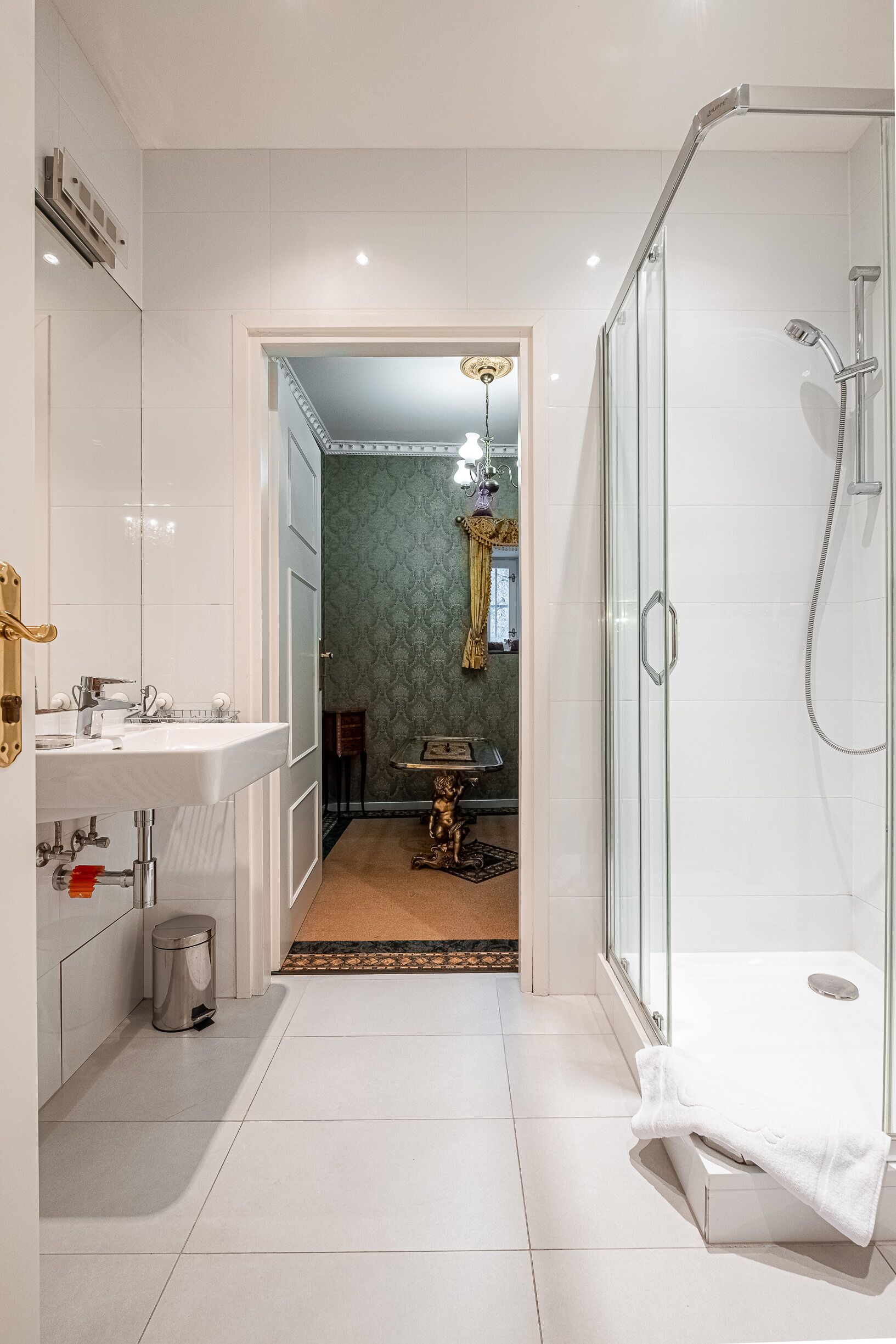 A modern bathroom with a glass-enclosed shower, a white sink, and a vanity.