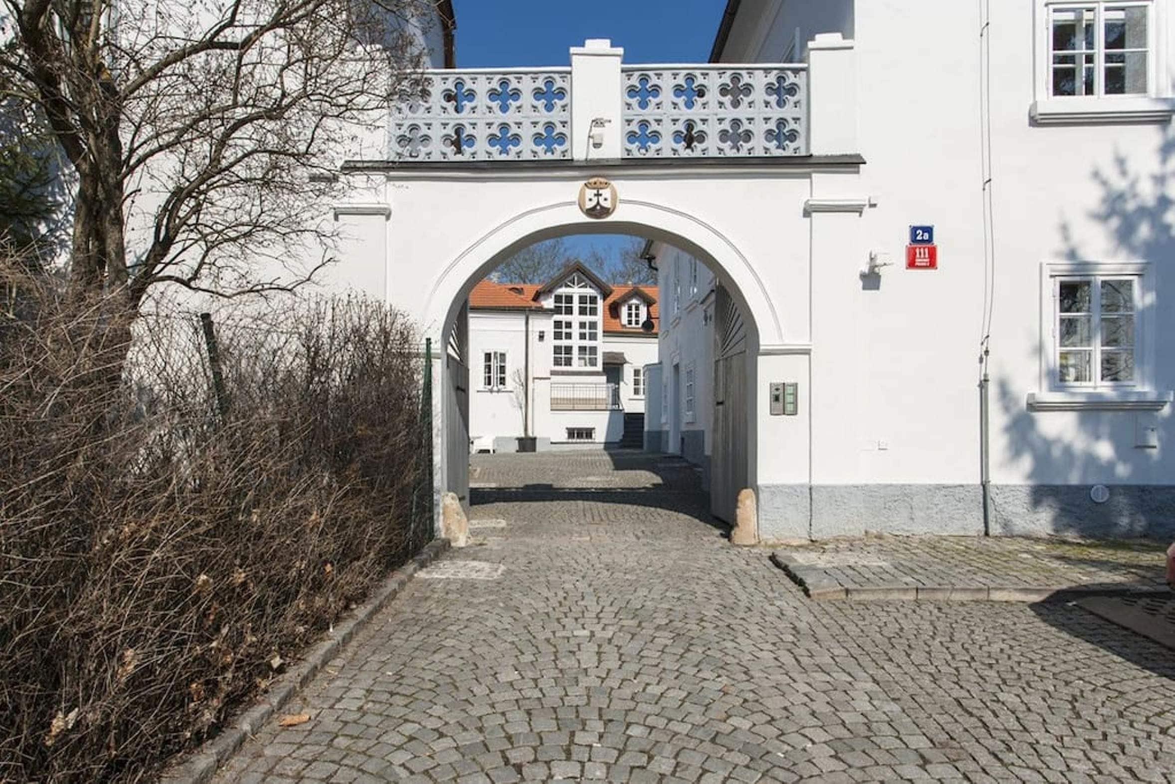 Una calle adoquinada que conduce a un edificio blanco con un arco decorativo.