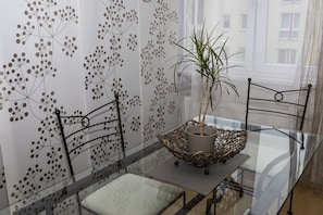 Un espace repas moderne avec une table en verre, des chaises en métal et un arrangement floral décoratif en guise de centre de table.