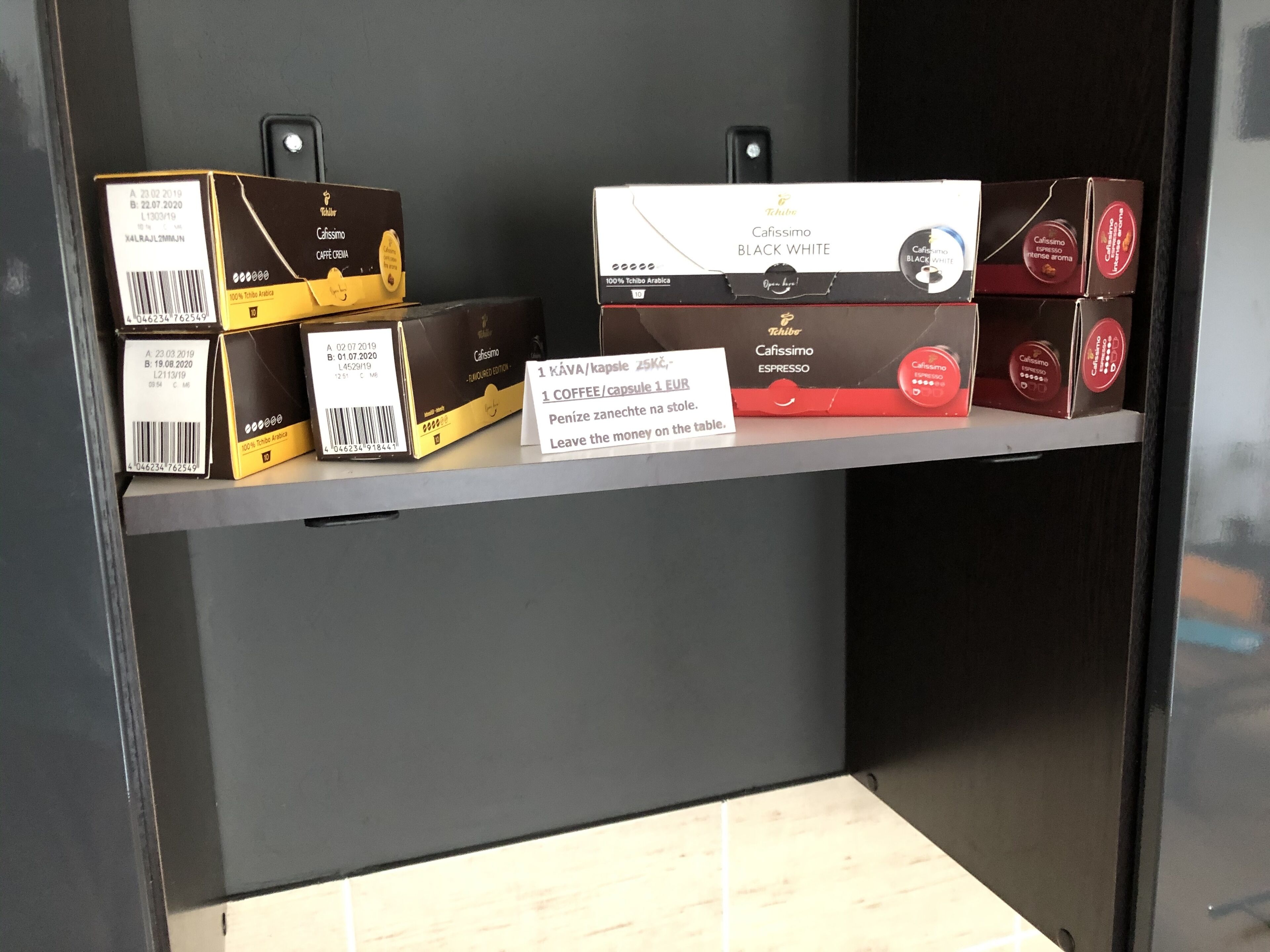 Een plank met diverse koffieproducten, waaronder dozen met de aanduiding 'Caffissimo Black White' en 'Espresso'.