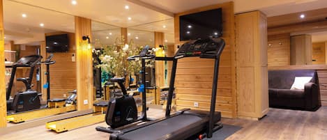 Un gimnasio con equipo de ejercicio, una cinta de correr y un espejo que refleja el espacio.