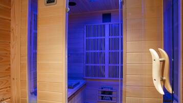 A sauna room with wooden walls, a bench, and a control panel.