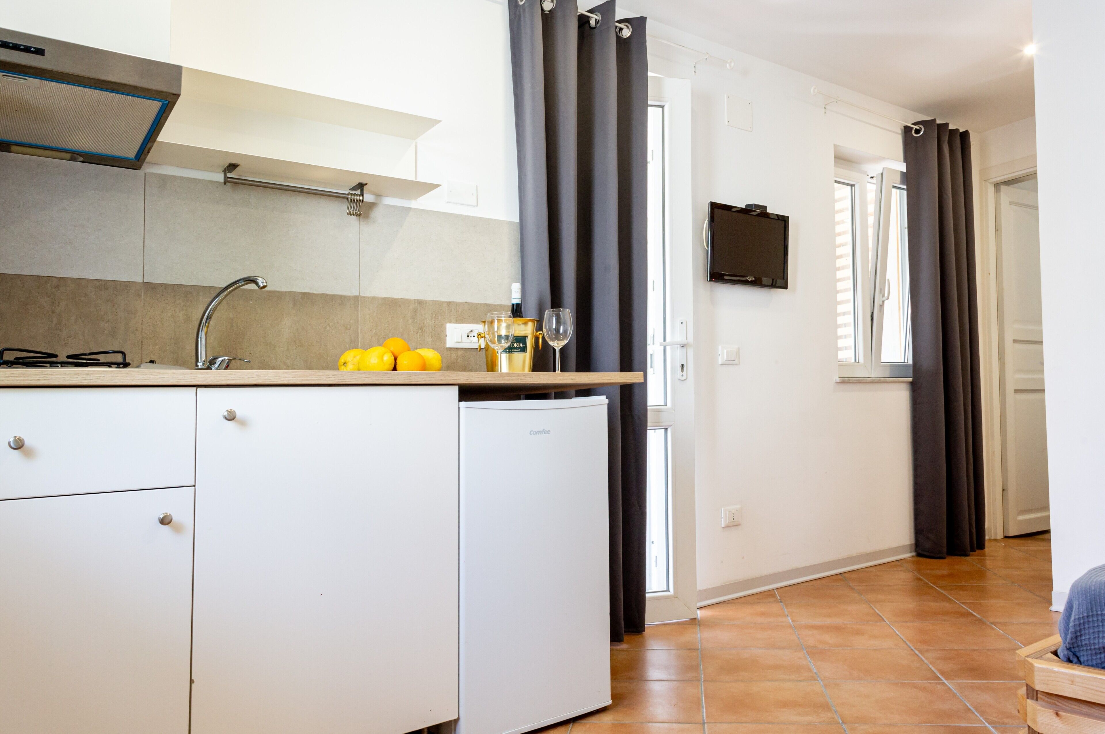 Eine kleine Küche mit integriertem Kühlschrank, einer Spüle und einer Arbeitsplatte.