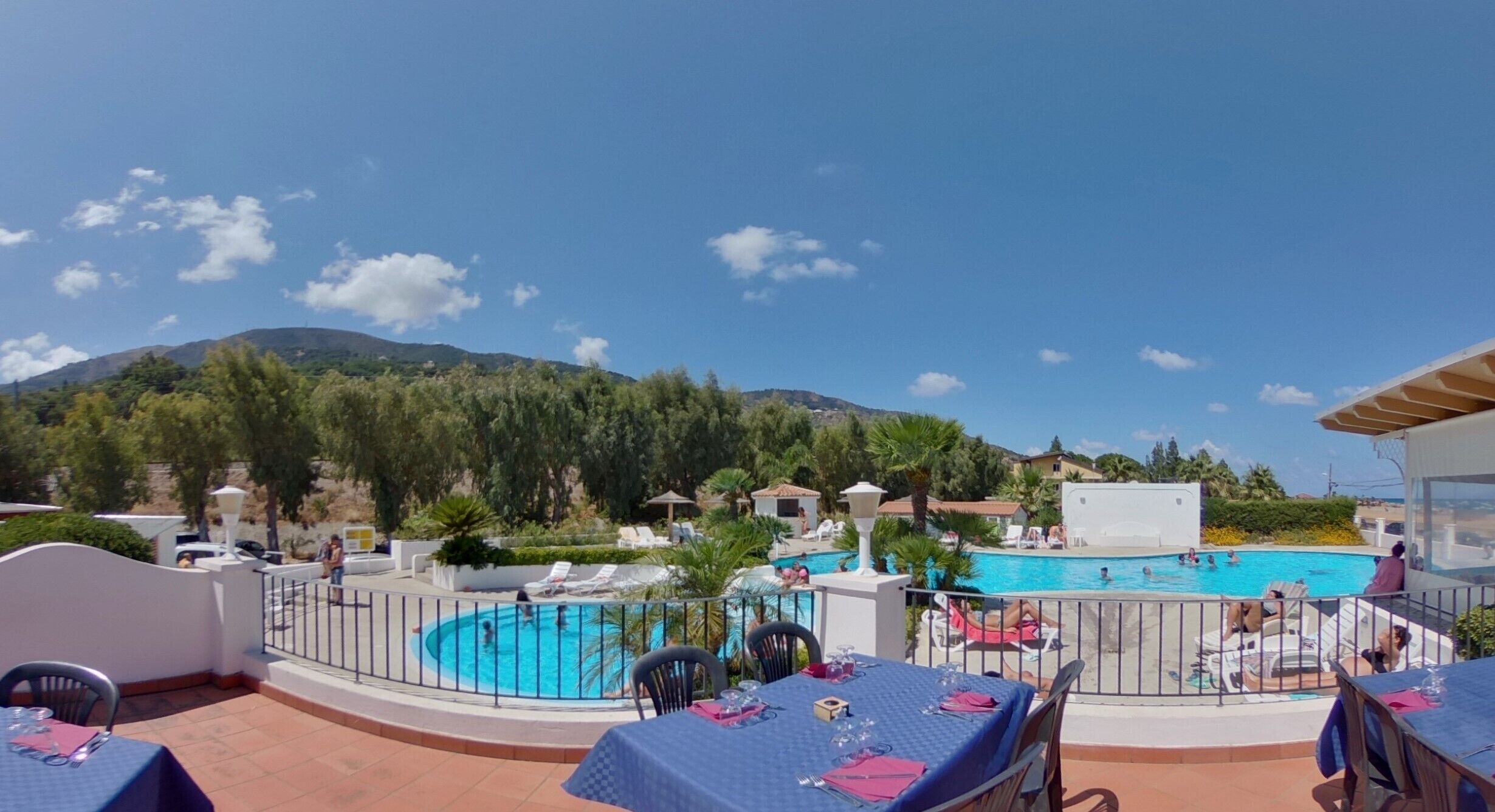 A poolside area with a view of a mountain, outdoor seating, and a swimming pool.
