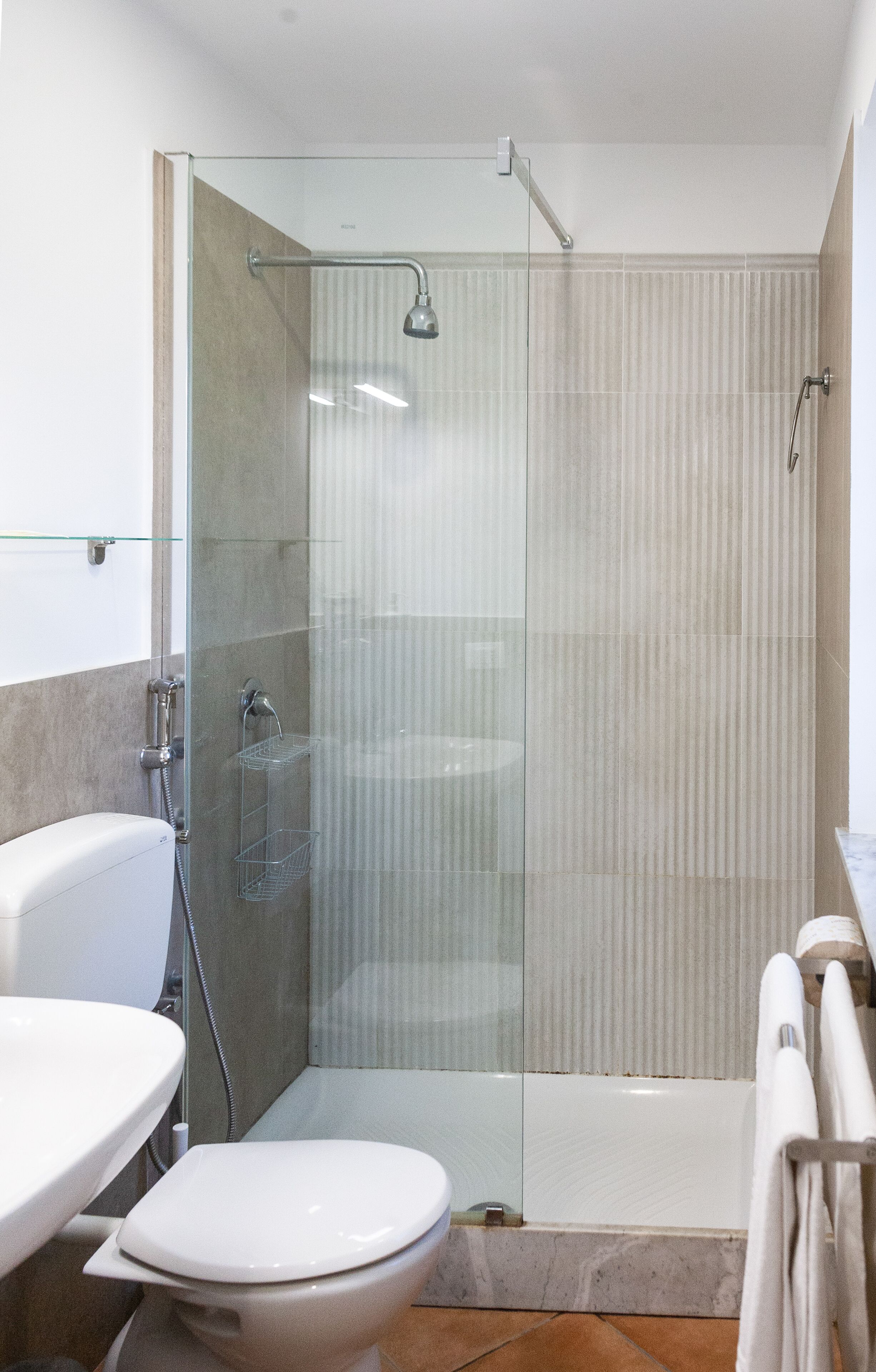 Un baño moderno con ducha de vidrio, inodoro blanco y lavamanos.