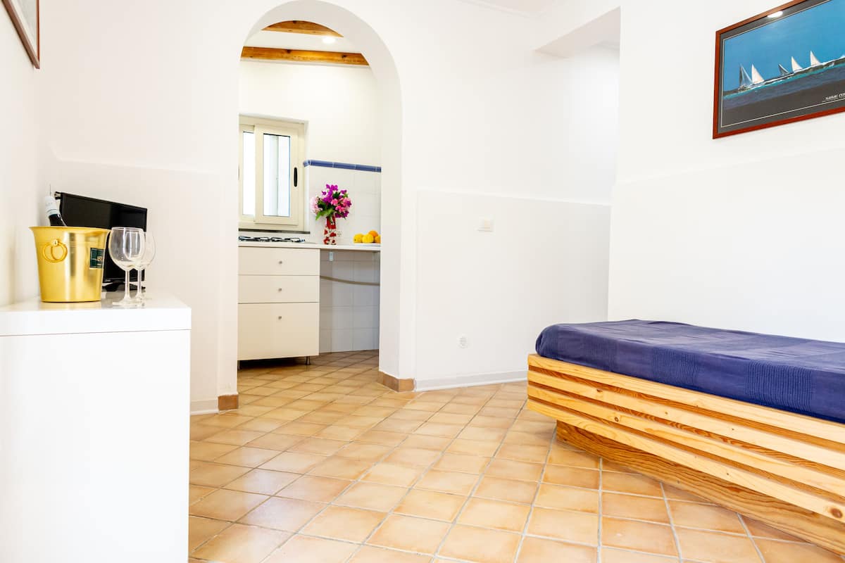 Een compacte kamer met een bed, een kitchenette en een eethoek.