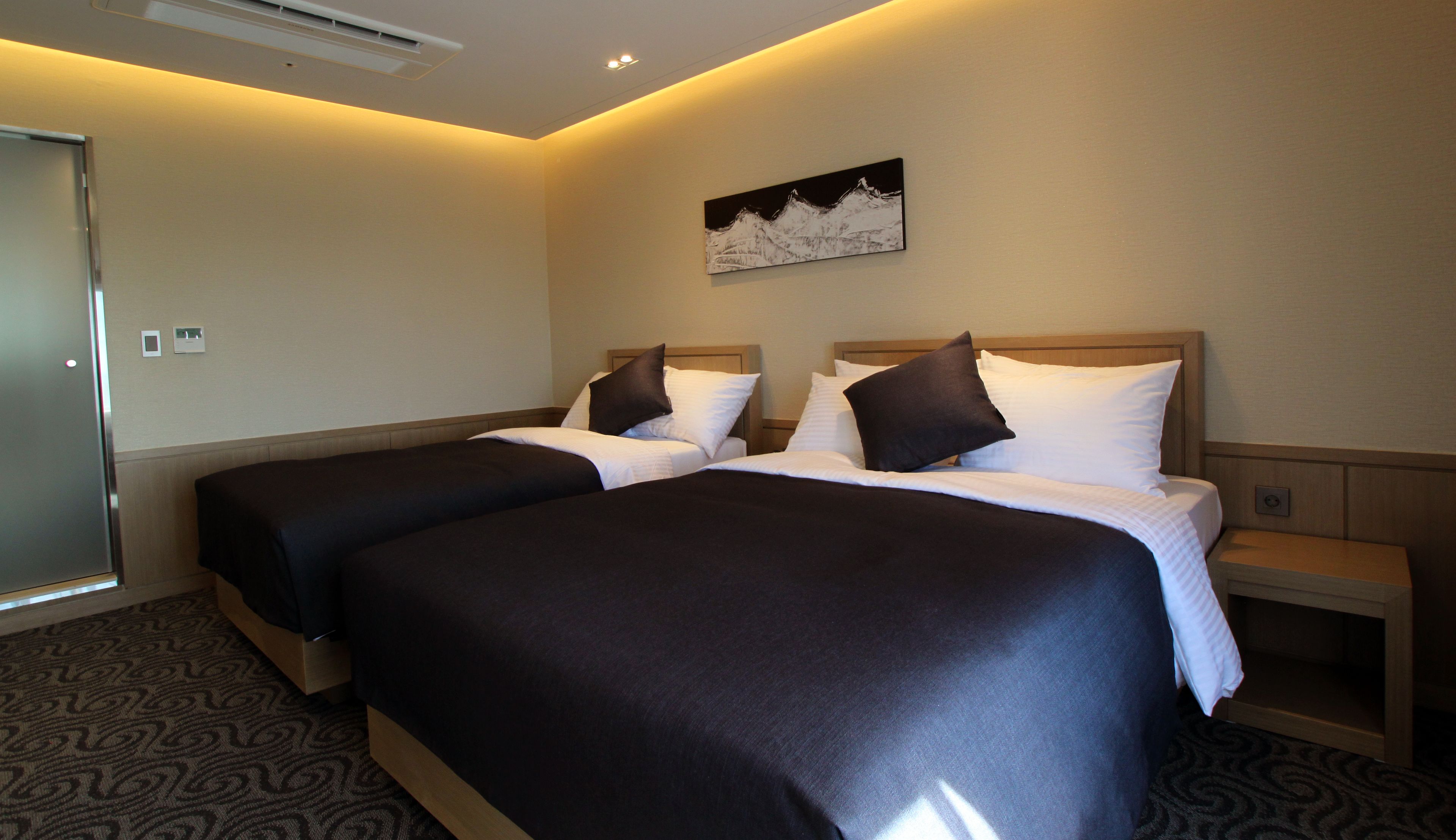 A hotel room with two beds, a painting on the wall, and a carpeted floor.