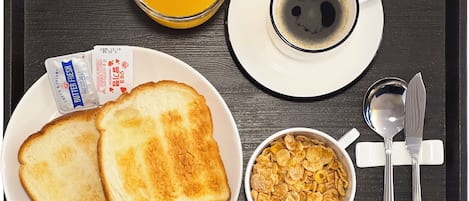 Uma bandeja com torradas, uma tigela de cereal, uma xícara de café e um copo de suco de laranja.