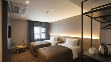 A hotel room with two beds, a desk, a chair, a TV, and a window with curtains.