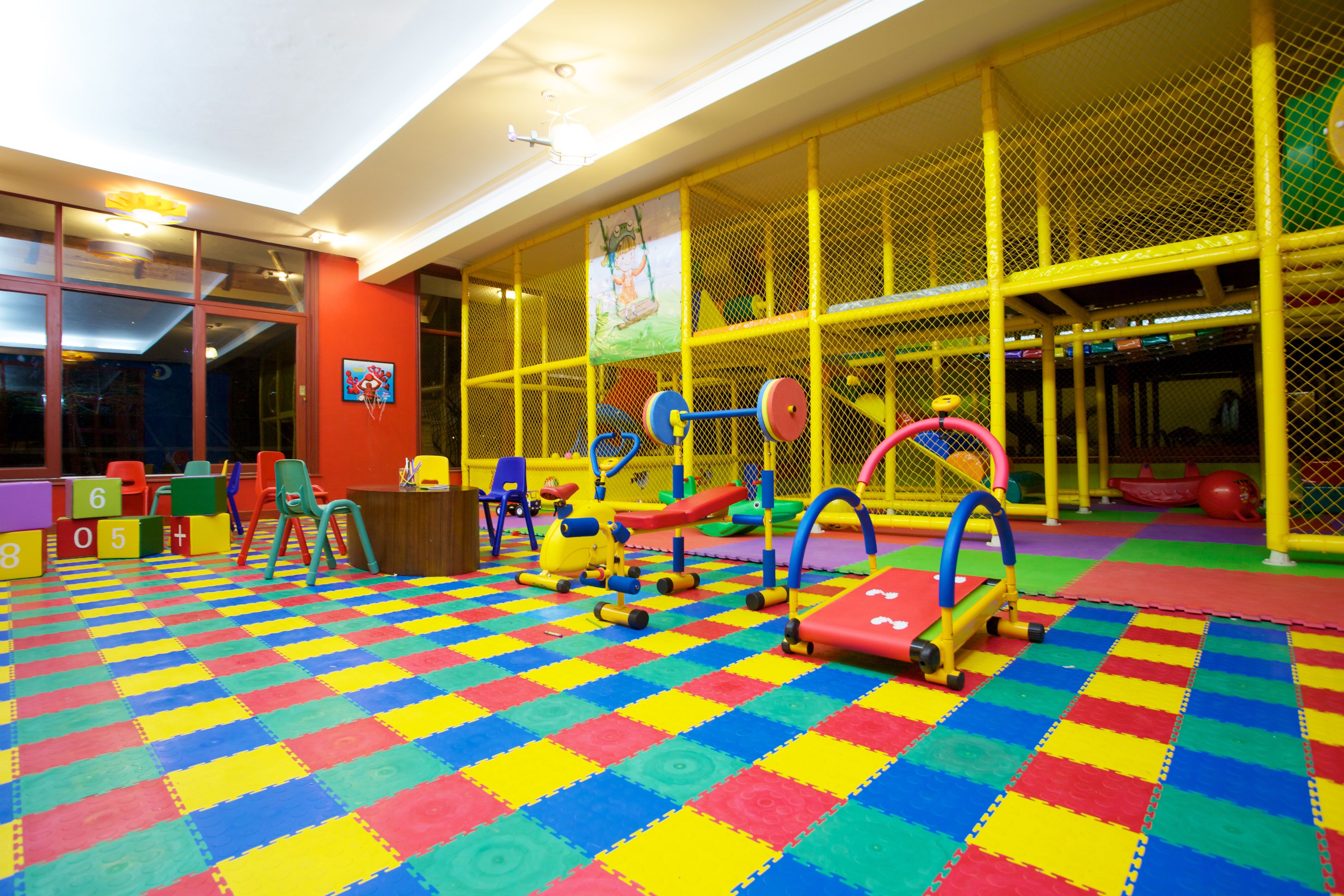 A play area with colorful interlocking foam mats, a climbing structure, and a soft play floor.