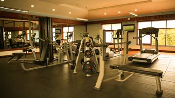 A gym with various exercise equipment, large windows, and a mirrored wall.