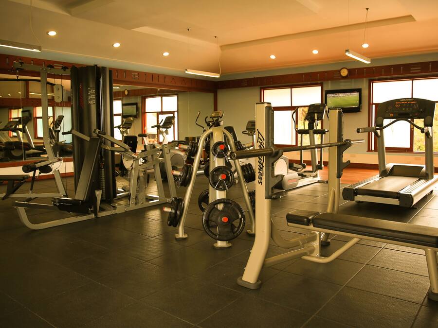 A gym with various exercise equipment, large windows, and a mirrored wall.