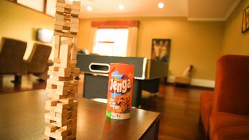 A wooden Jenga tower on a table with a can of Jenga in the background.