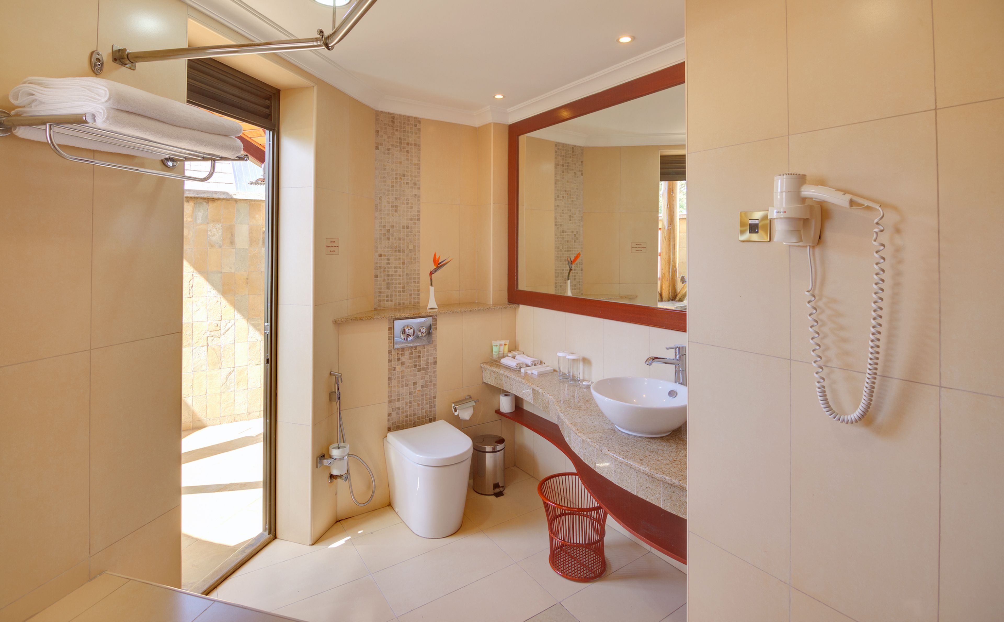 Un baño moderno con ducha, inodoro, lavamanos y un secador de pelo en la pared.