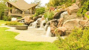 Une maison avec une cascade décorative dans le jardin.