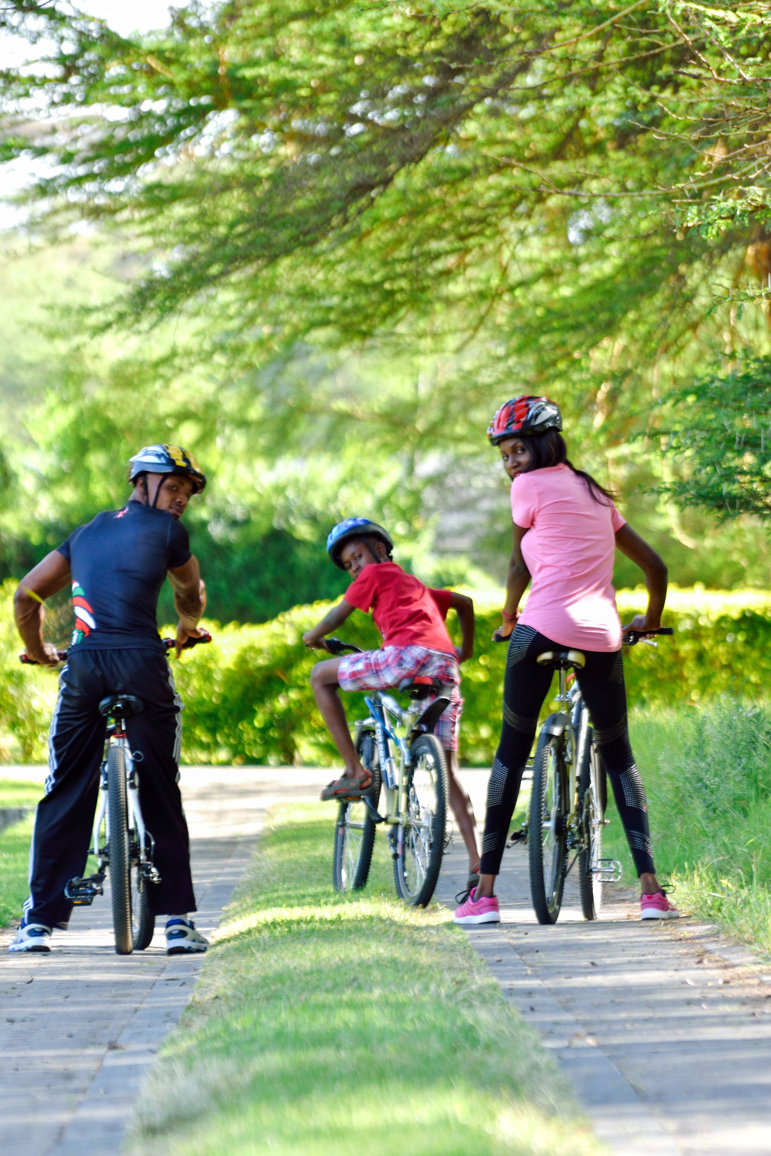 Un chemin bordé de verdure où l'on aperçoit trois personnes à vélo.