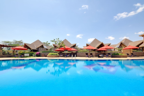 Een buitenzwembad, parasols bij het zwembad en ligstoelen