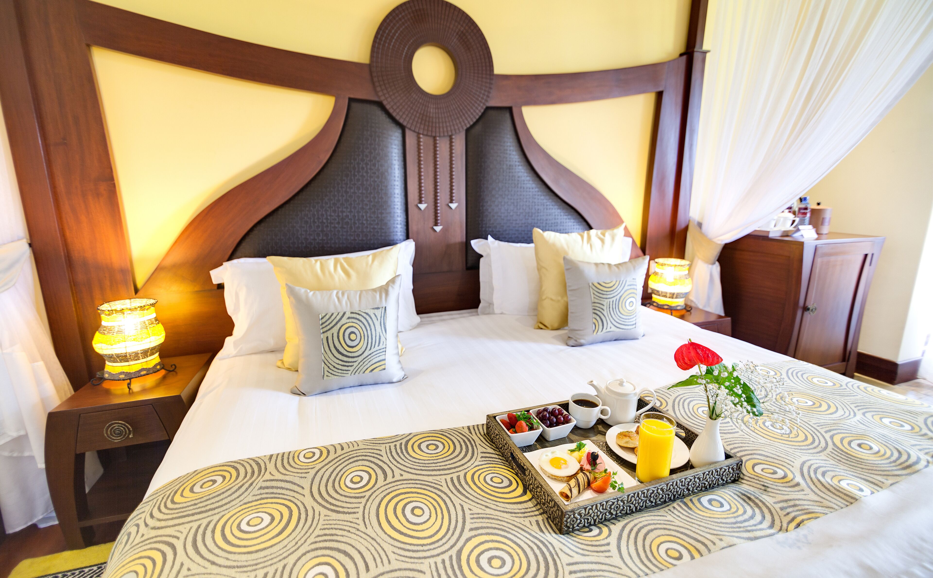 Una habitación de hotel con una cama grande, una bandeja de desayuno y una mesita de noche con lámpara.