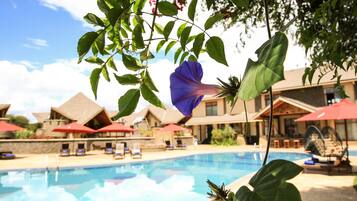 Una piscina al aire libre, sombrillas, sillones reclinables de piscina