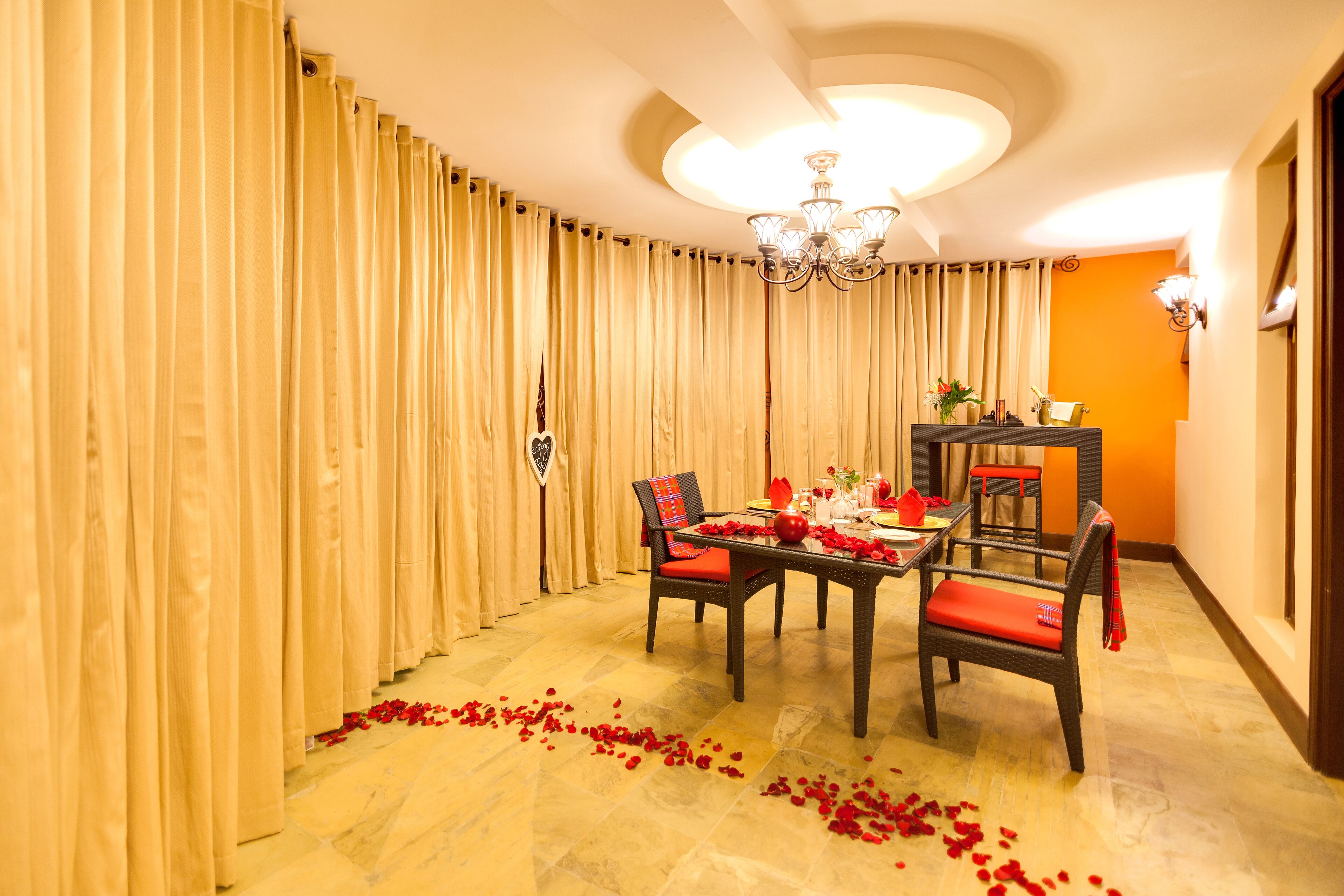 A dining area with a table set for four, surrounded by curtains and a chandelier.