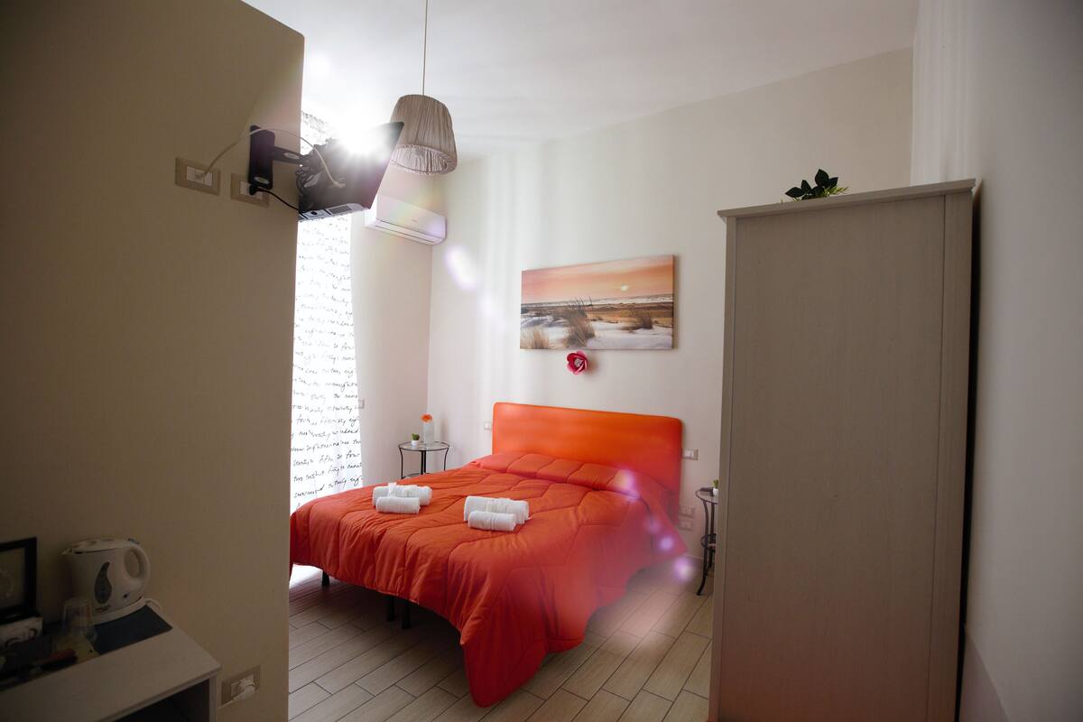A hotel room with a bed, a bedside table, a lamp, and a painting on the wall.