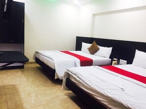 A hotel room with two beds, each with white bedding and red accents, a black headboard, and a flat-screen TV mounted on the wall. - Hotel Terminus Square (Mumbai)