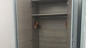 Un vestidor con terminación de madera, una barra para colgar ropa y un pequeño aparador.