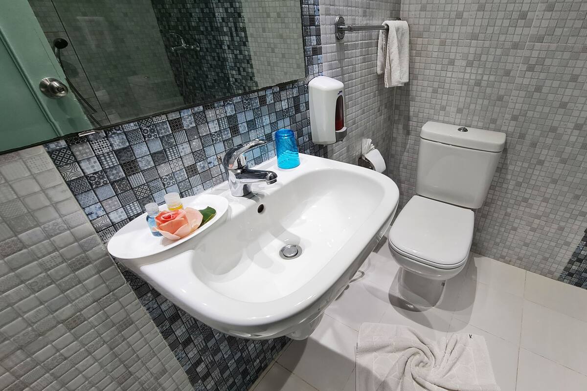 A bathroom with a white sink, a toilet, and a shower area.