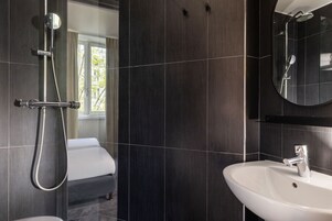 Un baño moderno con ducha, lavamanos y un espejo grande.