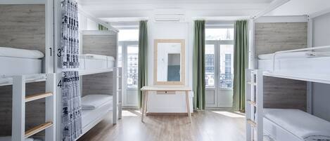 A room with bunk beds, a desk, and a window with curtains.