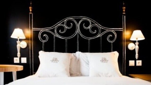 A bed with a metal headboard, two pillows, and two bedside lamps.