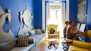 A room with a blue wall, a sofa, a yellow armchair, and a table. There is a chalkboard on the wall with writing.