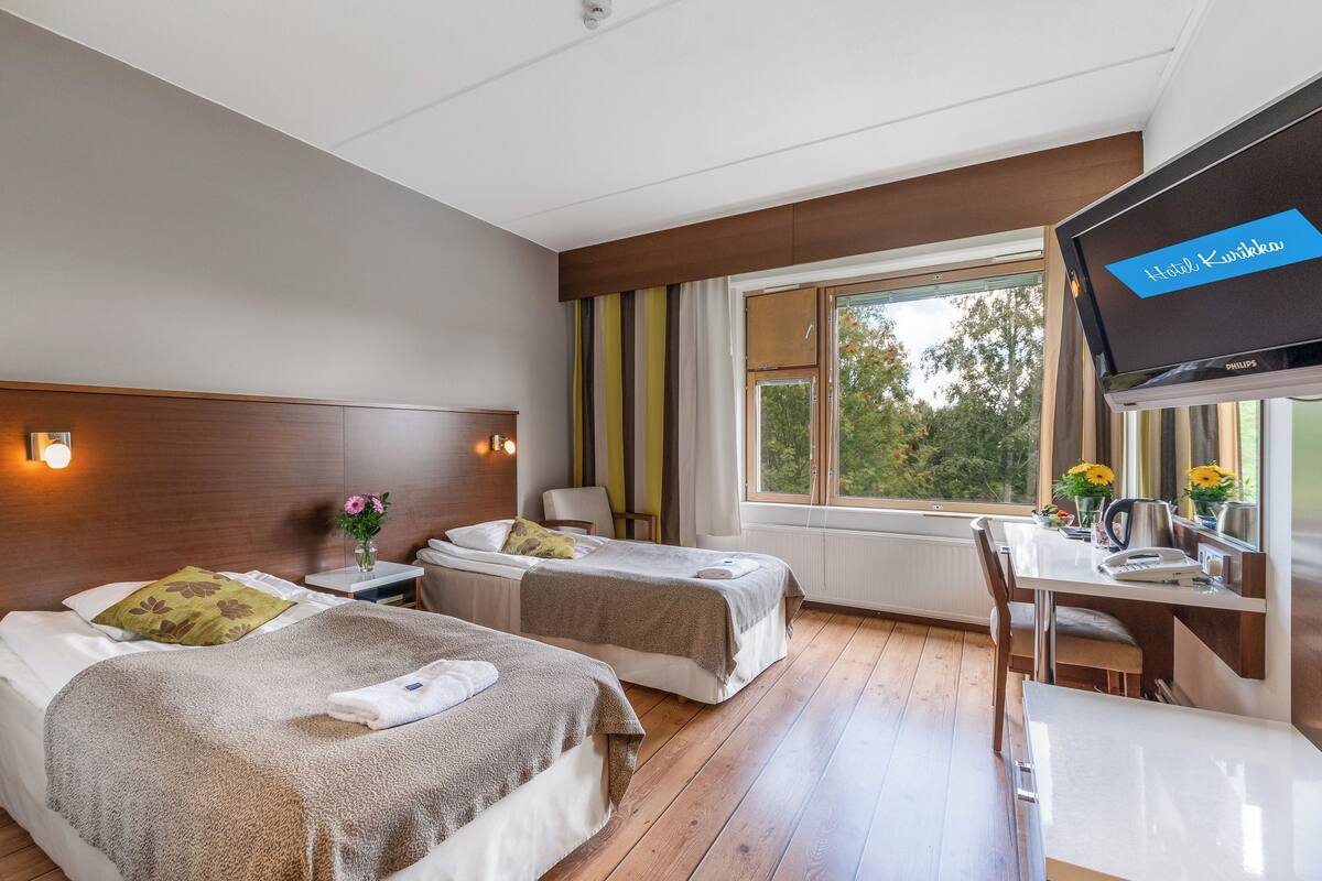 Habitación de hotel con dos camas, un escritorio y una televisión.