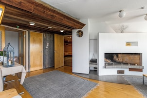 Uma sala de estar moderna com lareira, teto de madeira e um tapete grande.