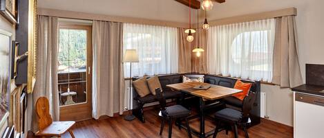 A cozy dining area with a wooden table and benches, a view of the outdoors through large windows, and a rustic ceiling with exposed beams.