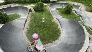 A child riding a bicycle on a curved concrete path surrounded by grass and gravel. - A CASA Juwel - Ski in & Out Appartements (Soelden)