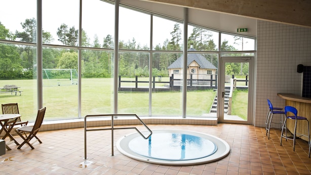 Une piscine intérieure donnant sur un champ verdoyant et une structure en bois.