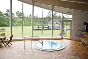 Une piscine intérieure donnant sur un champ verdoyant et une structure en bois.