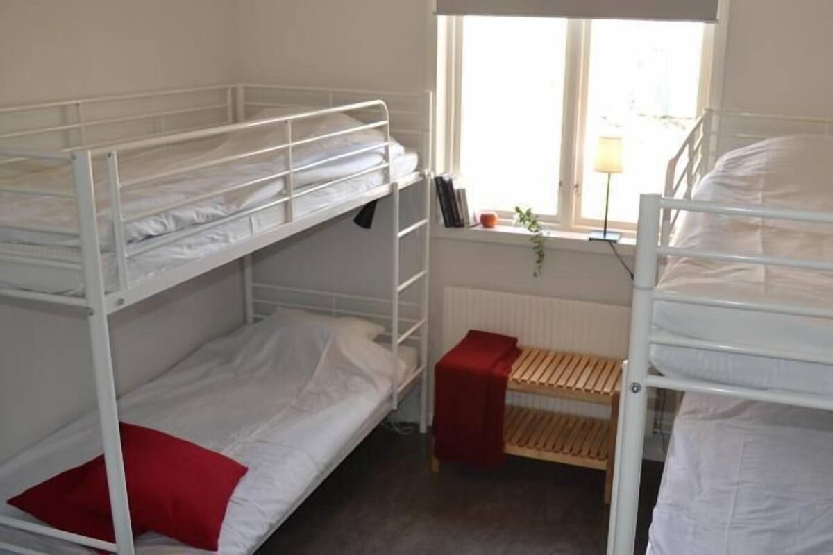 Un dormitorio con literas, una ventana con vistas y un radiador.