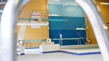 Una piscina interior con una plataforma de salto, un flotador salvavidas y un mural en la pared.