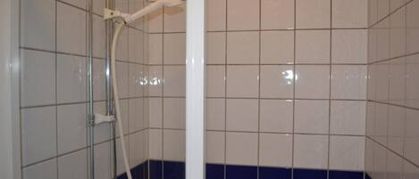 Un espacio de ducha con azulejos, un cabezal de ducha de mano y un tubo vertical.