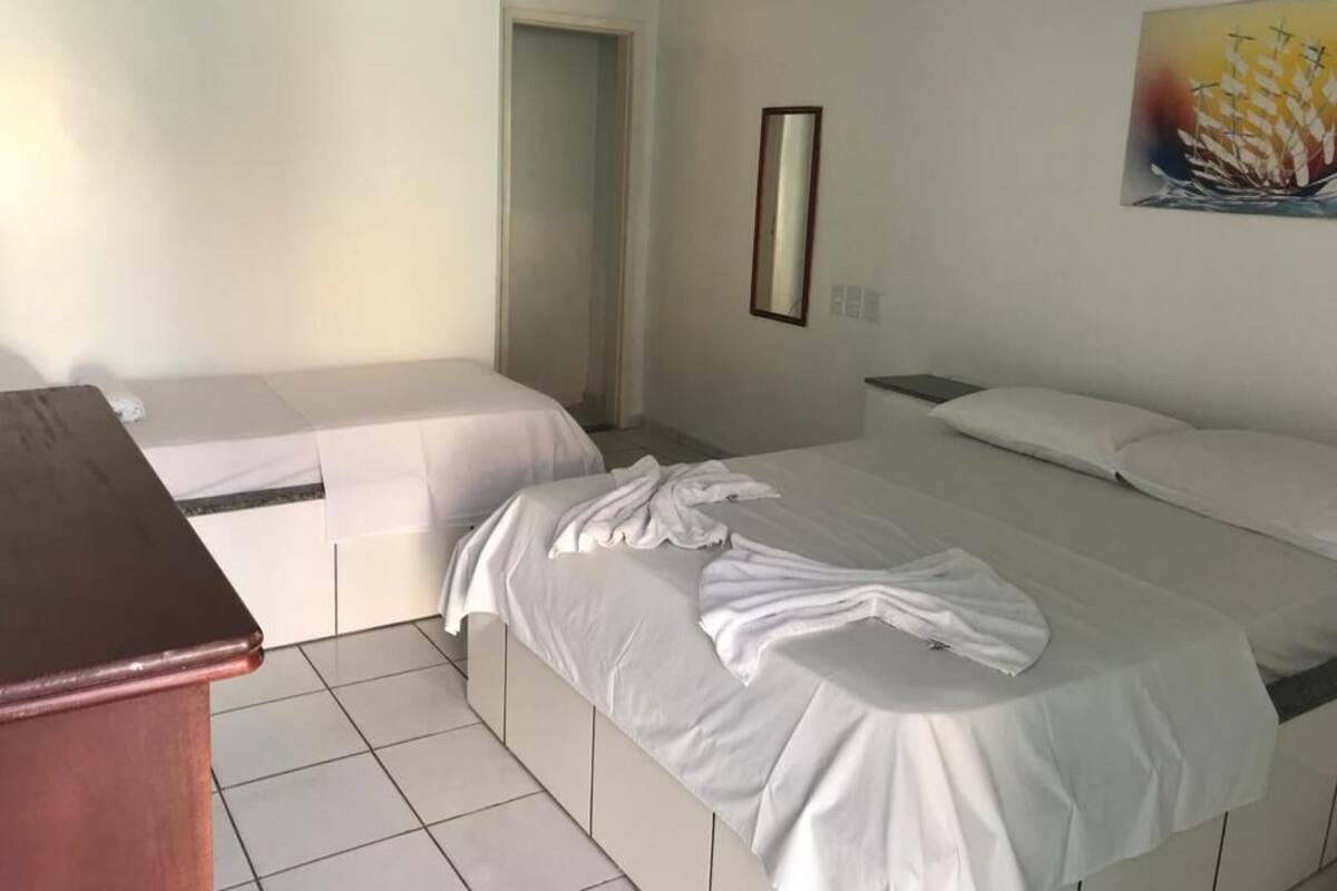 A hotel room with two beds, a desk, and a painting on the wall.