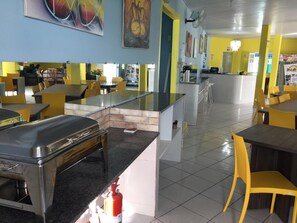 A restaurant with a central bar area, multiple tables and chairs, and a tiled floor. - Pousada Ilha do Sol (Salinópolis)