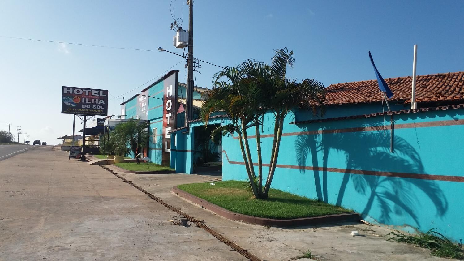 Um hotel com uma placa anunciando "HOTEL ILHA DO SOL" e um número de contato.
