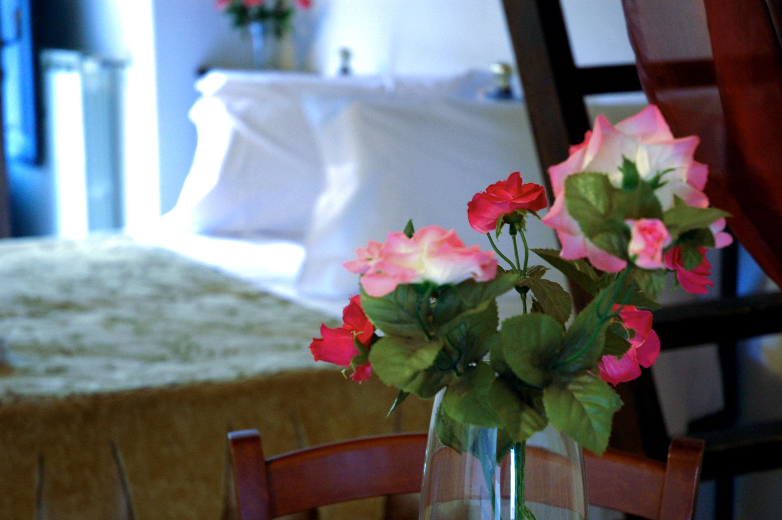 A table with a vase of pink and red flowers.