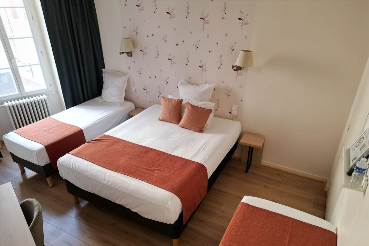 Ein Hotelzimmer mit zwei Betten, einem kleinen Tisch, einem Stuhl und einer Heizung.