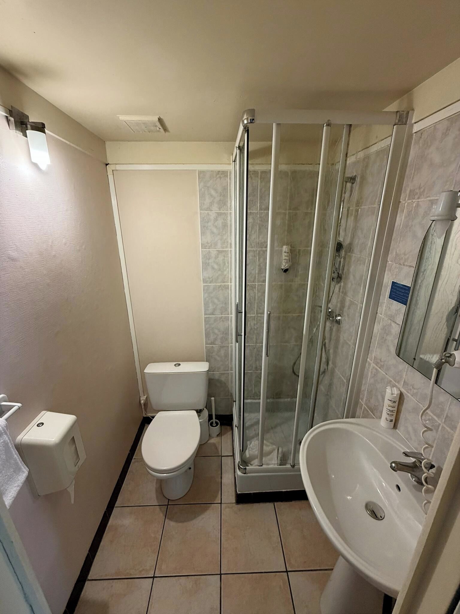 A compact bathroom with a toilet, a glass-enclosed shower, and a sink.